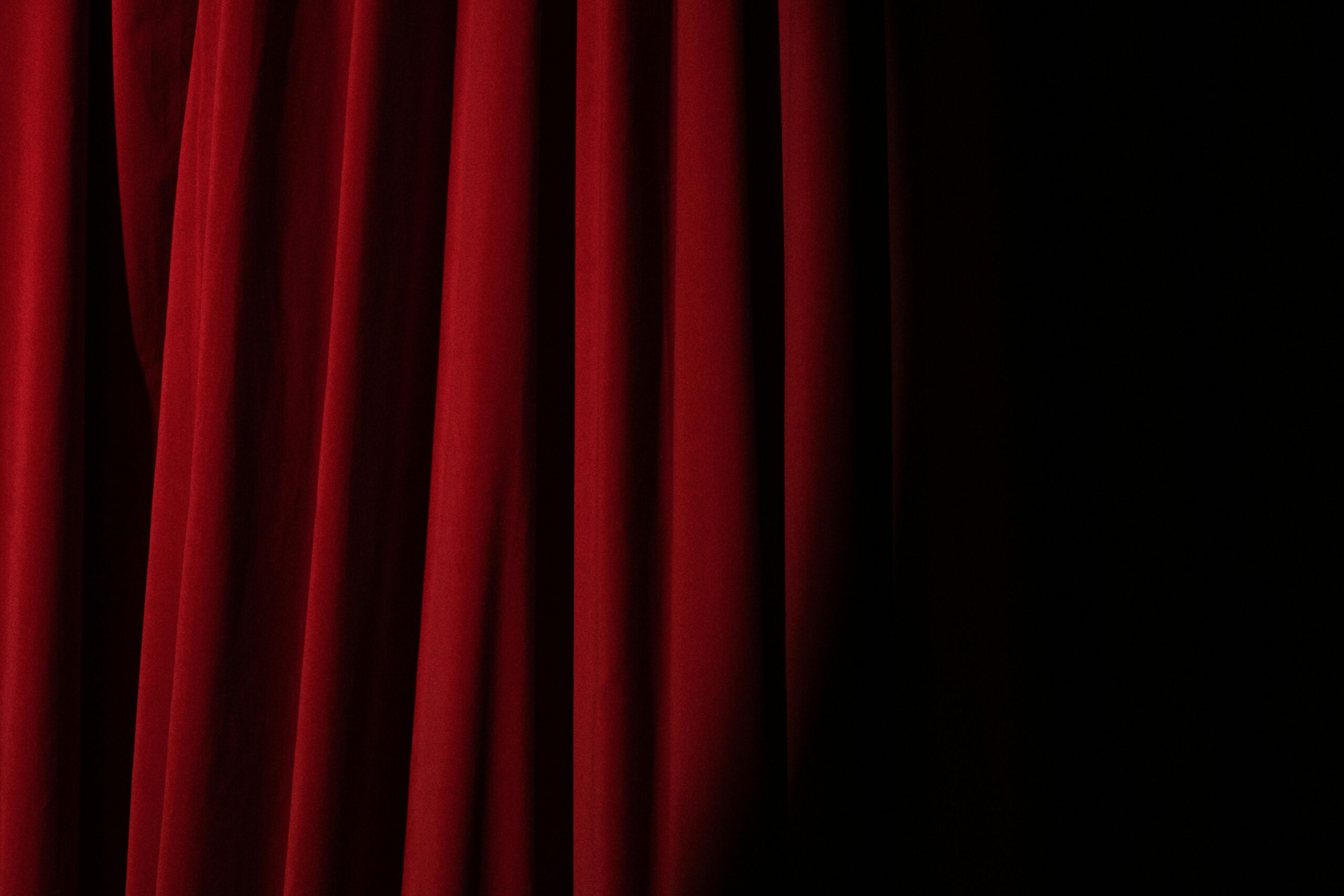 Elegant red velvet curtain with dramatic lighting perfect for theater themes.